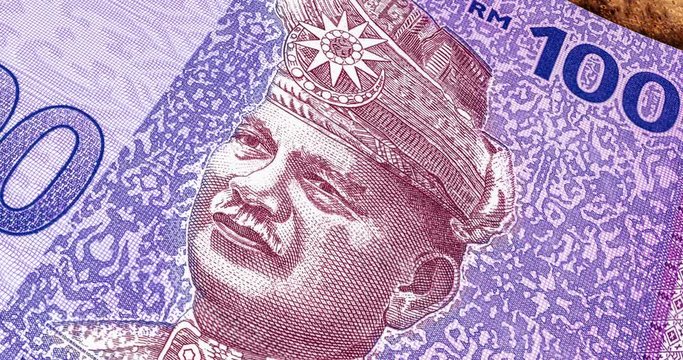 Extreme close up footage, panning over over one hundred Ringgit Malaysia. Detailed close up of new RM 100. Macro shot from the front of Malaysian money with the portrait of the first King or Agong.