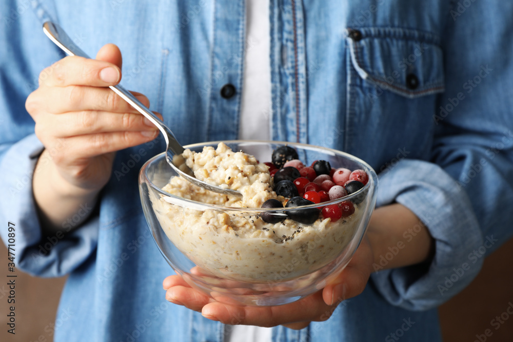 Wall mural Woman holds bowl with oatmeal porridge with fruits. Close up