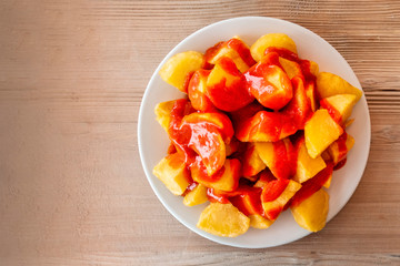 Patatas bravas, typical Spanish food. Potato with a spicy sauce, shot from the top on a wooden table with a place for text