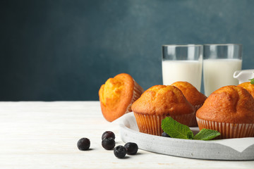 Composition with muffins and milk on white wooden background