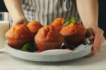 Woman holds tray with muffins, close up. Muffins and milk