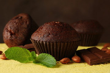 Composition with tasty muffins, chocolate and nuts on yellow table
