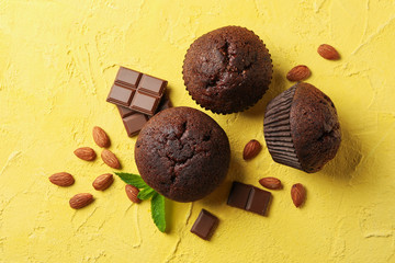 Delicious muffins, chocolate and almond on yellow background