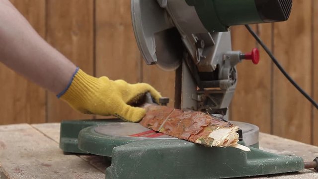 cut a wooden board on an electric saw