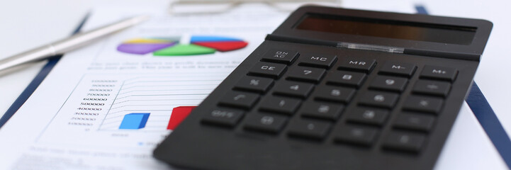 Obraz premium The black calculator lies on a chessboard.