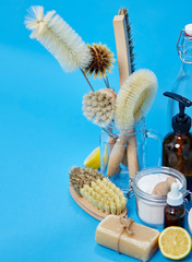 natural cleaning stuff, sustainability and eco living concept - lemon halves, washing soda, bottle of vinegar with laundry and liquid soap and brushes on blue background
