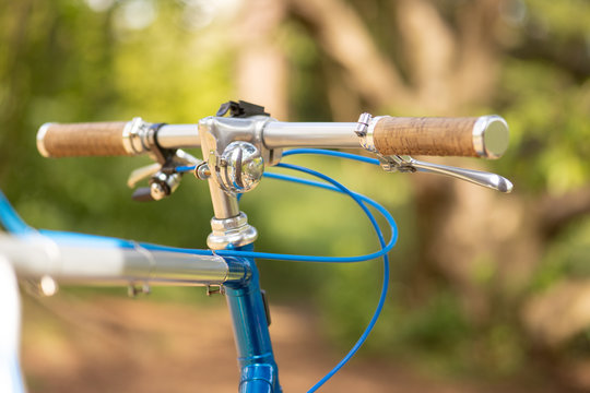 Detail Of A Beautiful Customized Retro Bicycle Focusing On The Handlebar With A Blurry Park And Trees In The Background