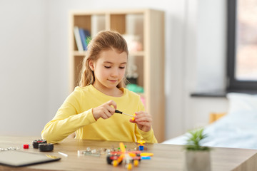 children, technology and science concept - happy girl playing with robotics kit at home
