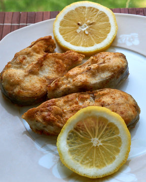 Pieces of fried fish with lemon wedges.
