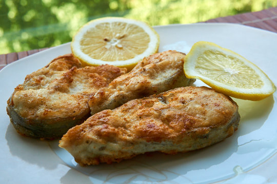 Pieces of fried fish with lemon wedges.