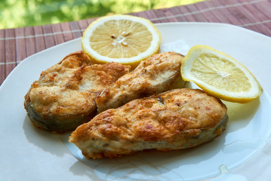 Pieces of fried fish with lemon wedges.