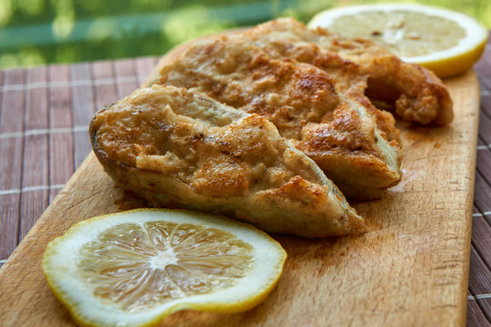 Pieces of fried fish with lemon wedges.
