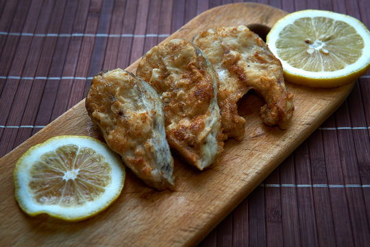 Pieces of fried fish with lemon wedges.