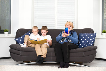 Children read a book, and grandmother plays on a mobile phone.A social problem.	