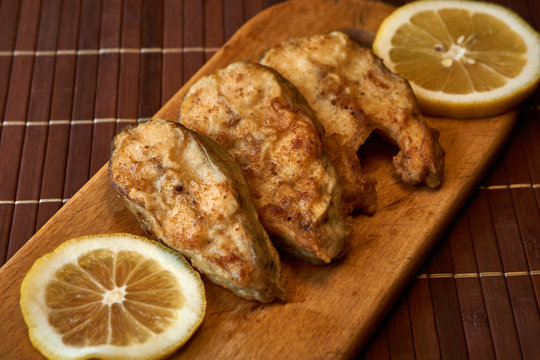 Pieces of fried fish with lemon wedges.
