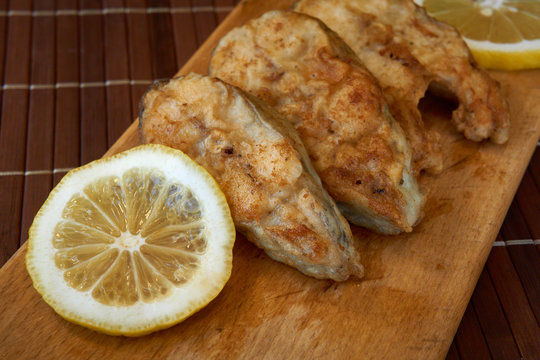 Pieces of fried fish with lemon wedges.