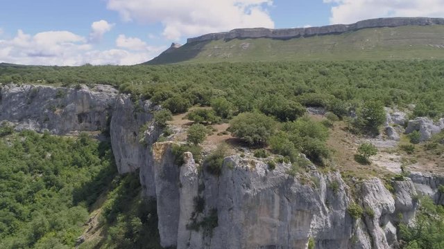 AERIAL DRONE ORBIT SHOT OF BEAUTIFUL GREEN FOREST OVER ROCKY MESETA MOUNTAIN AND VALLEY 
