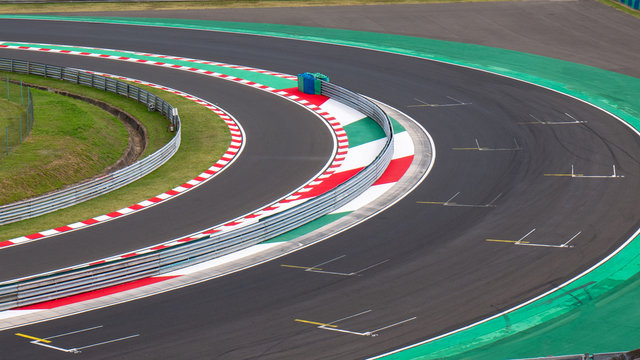 Motor racing circuit Red and White Kerb. A race track bend with grid signs and wheel arches.