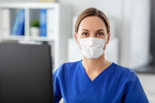 Medicine, Technology And Healthcare Concept - Female Doctor Or Nurse Wearing Face Protective Medical Mask For Protection From Virus Disease With Computer Working At Hospital