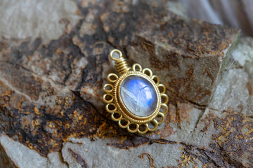 Brass pendant with natural moon stone gemstone on rocky background - 347721476