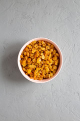 Golden Raisins in a Pink Bowl on a gray surface, top view. Flat lay, overhead, from above.