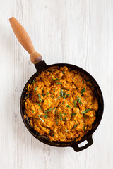 Homemade Chicken Tikka Masala in a cast iron pan on a white wooden background, top view. Flat lay, overhead, from above.