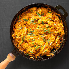 Homemade Chicken Tikka Masala in a cast iron pan on a black background, top view. Flat lay, overhead, from above. Close-up.