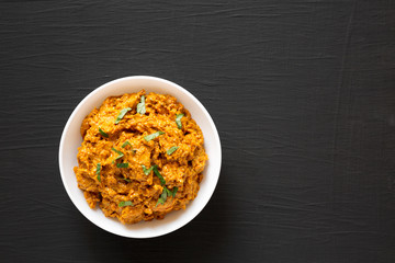 Homemade Chicken Tikka Masala in a white bowl on a black background, top view. Flat lay, overhead, from above. Copy space.