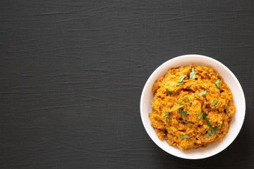 Homemade Chicken Tikka Masala in a white bowl on a black background, top view. Flat lay, overhead, from above. Copy space.