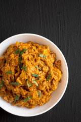 Homemade Chicken Tikka Masala in a white bowl on a black background, top view. Flat lay, overhead, from above. Space for text.
