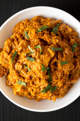 Homemade Chicken Tikka Masala in a white bowl on a black surface, top view. Flat lay, overhead, from above.