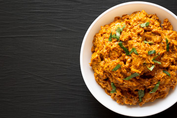 Homemade Chicken Tikka Masala in a white bowl on a black surface, top view. Flat lay, overhead, from above. Copy space.