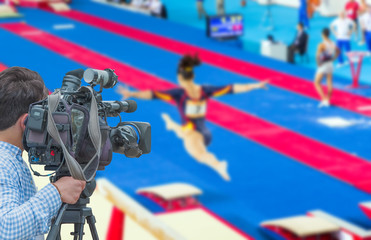 Cameraman shooting live broadcast from gymnastics game to television and internet on the background...