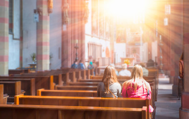 People praying in a church with sun rays - obrazy, fototapety, plakaty
