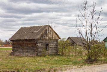 Fototapeta na wymiar Abandoned old wooden house among the trees. Rural spring landscape.