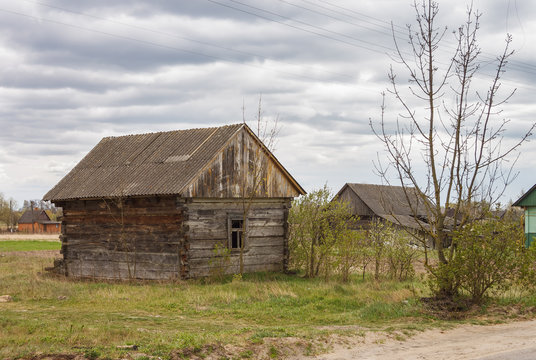 Abandoned old wooden house among the trees. Rural spring landscape.