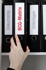 BCG-Matrix – Finanzen/Statistik. Ordner im Büro-Regal. Hand greift Unterlagen im Schrank. Beschriftung mit Wort
