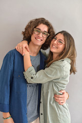 Young couple with eyeglasses standing on grey background, isolated