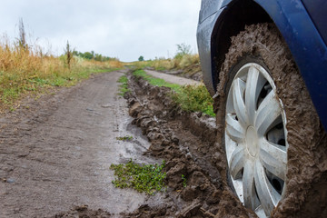 A car wheel stucking in mud on a rural unpaved road after the rain