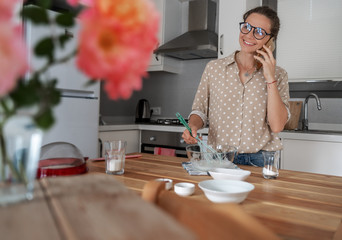 A young woman in the kitchen is preparing a dessert, whips the whites with a whisk and speaks on...