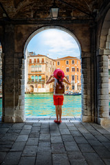 Eine Touristen Frau mit rotem Hut steht am Kanal Grande in Venedig, Italien, und schaut auf die...