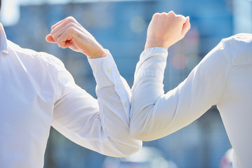 A close-up photo of elbow bumping. Elbow greeting to avoid the spread of coronavirus (COVID-19). Colleagues meet with bare hands. Instead of greeting with a hug or handshake, they bump elbows.