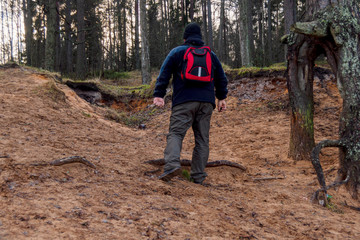 A man  in a forest near a lake with a backpack.