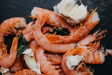 Raw shrimps with garlic, parsley on a dark concrete background. Seafood. Top view with copy space. Flat lay