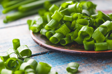 Fresh green onion chopped and lies on a bowl on a background of blue boards.