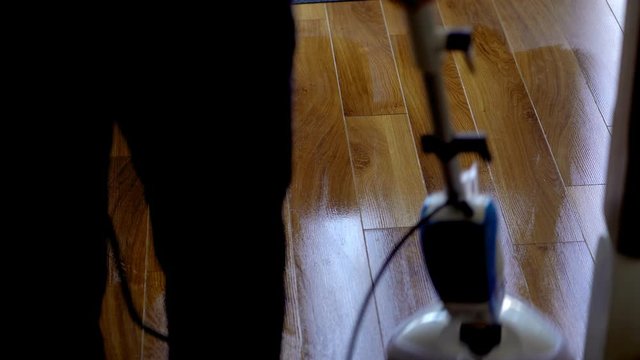 Man steam cleaning wooden floor wet mop