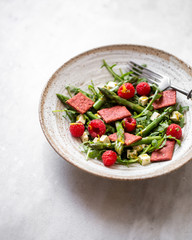 salad with asparagus, arugula, tofu and raspberries in rustic plate