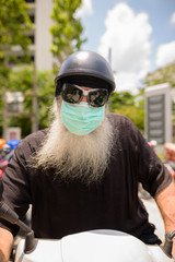 Face of mature bearded hipster man with sunglasses and mask riding motorcycle