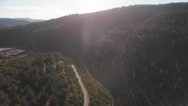 Jerusalem mountains aerial footage drone, golden hour sun sunset on a lonely road between the forest. pan up shot
