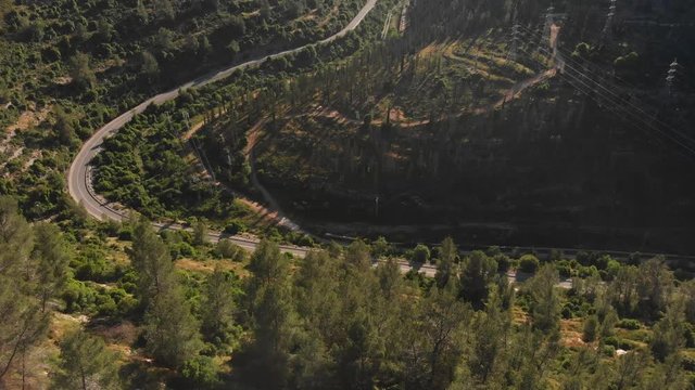 Jerusalem mountains aerial footage drone, golden hour sun sunset on a lonely road between the forest.